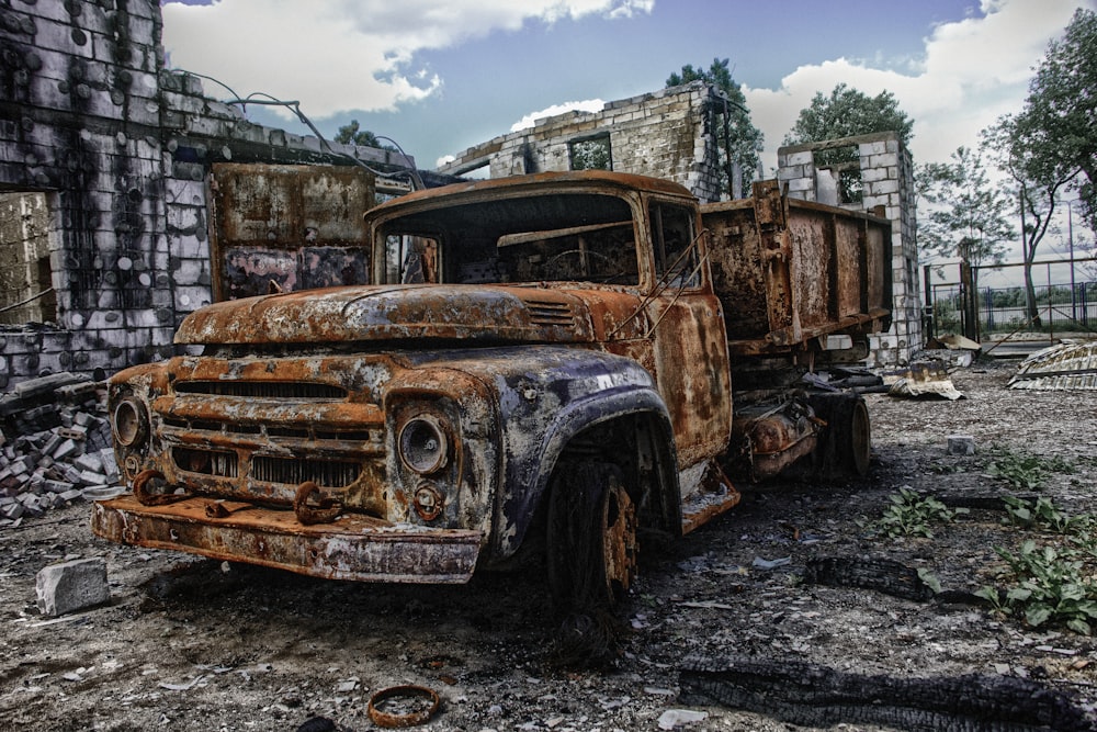 an old rusted truck sitting in the middle of a field