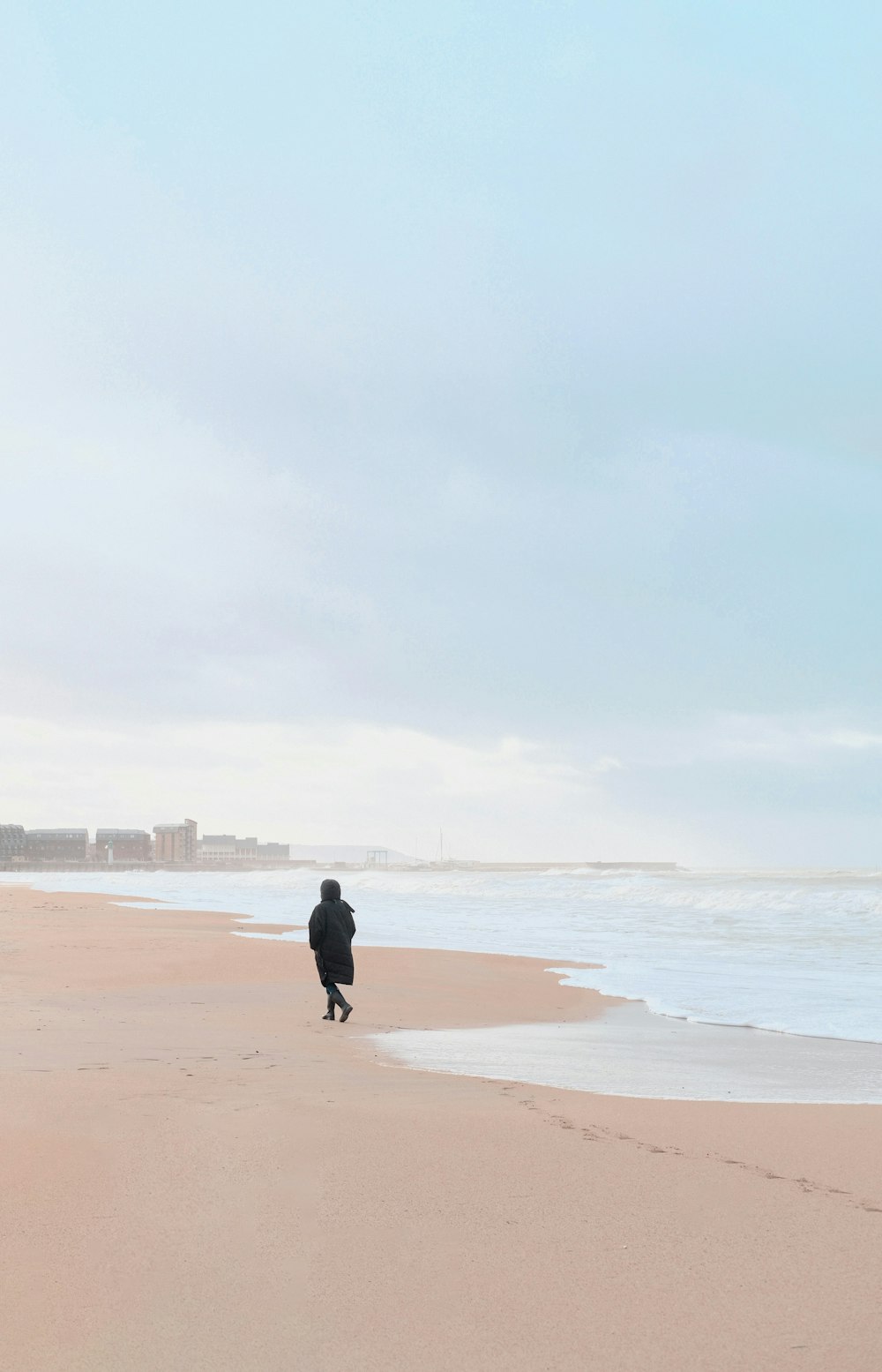 a person walking on a beach next to the ocean