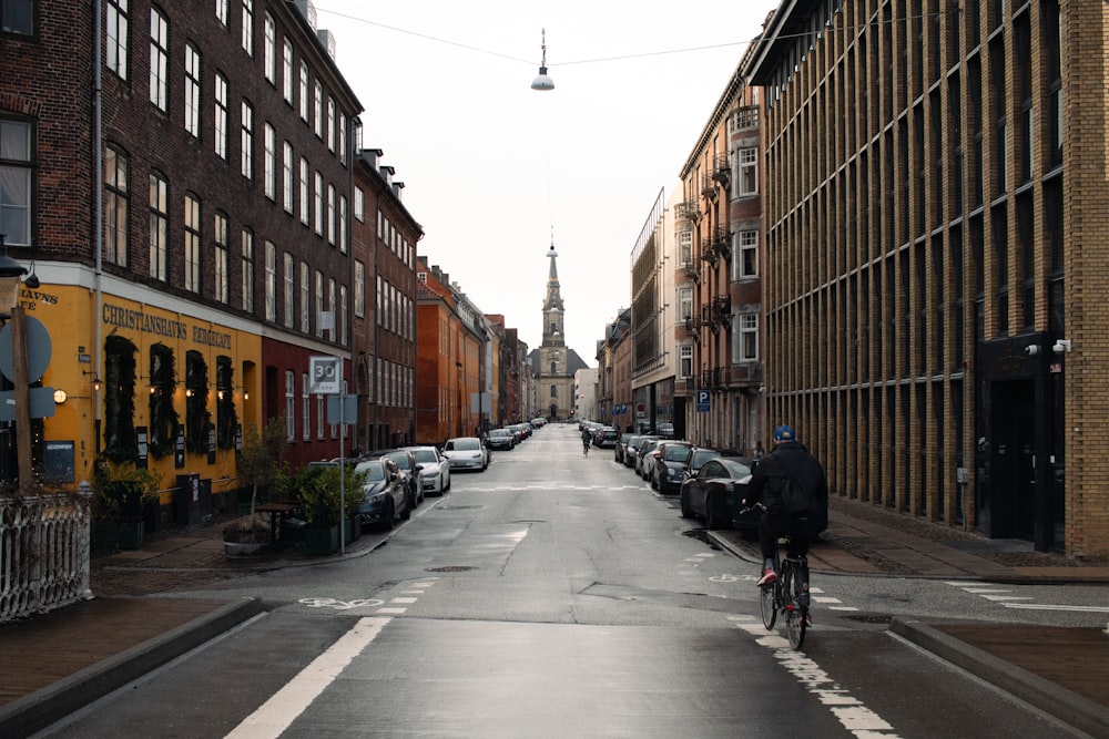 a man riding a bike down a street next to tall buildings