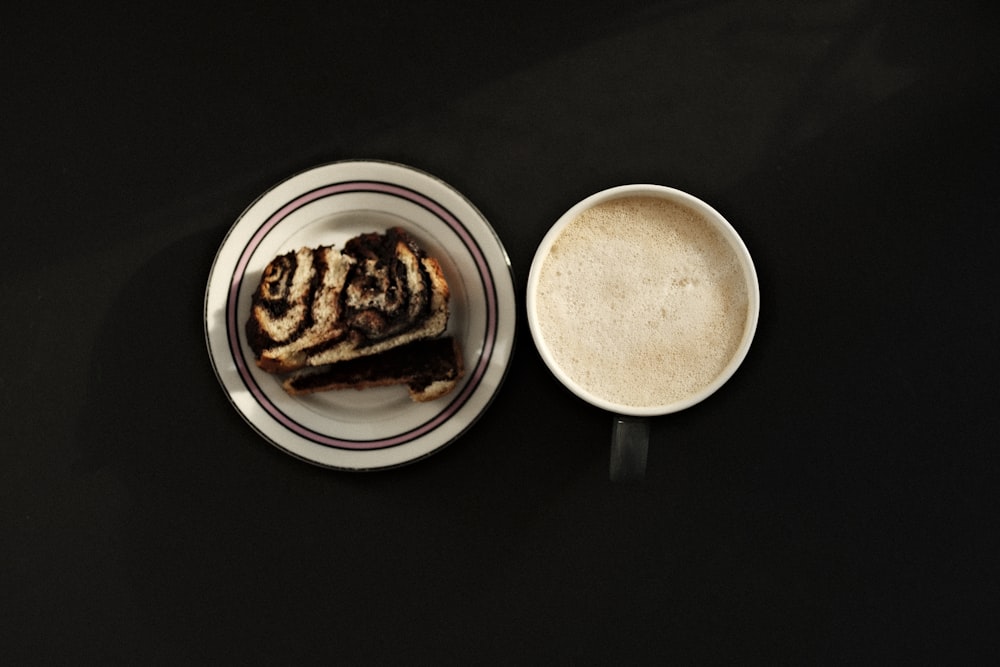 a piece of cake on a plate next to a cup of coffee