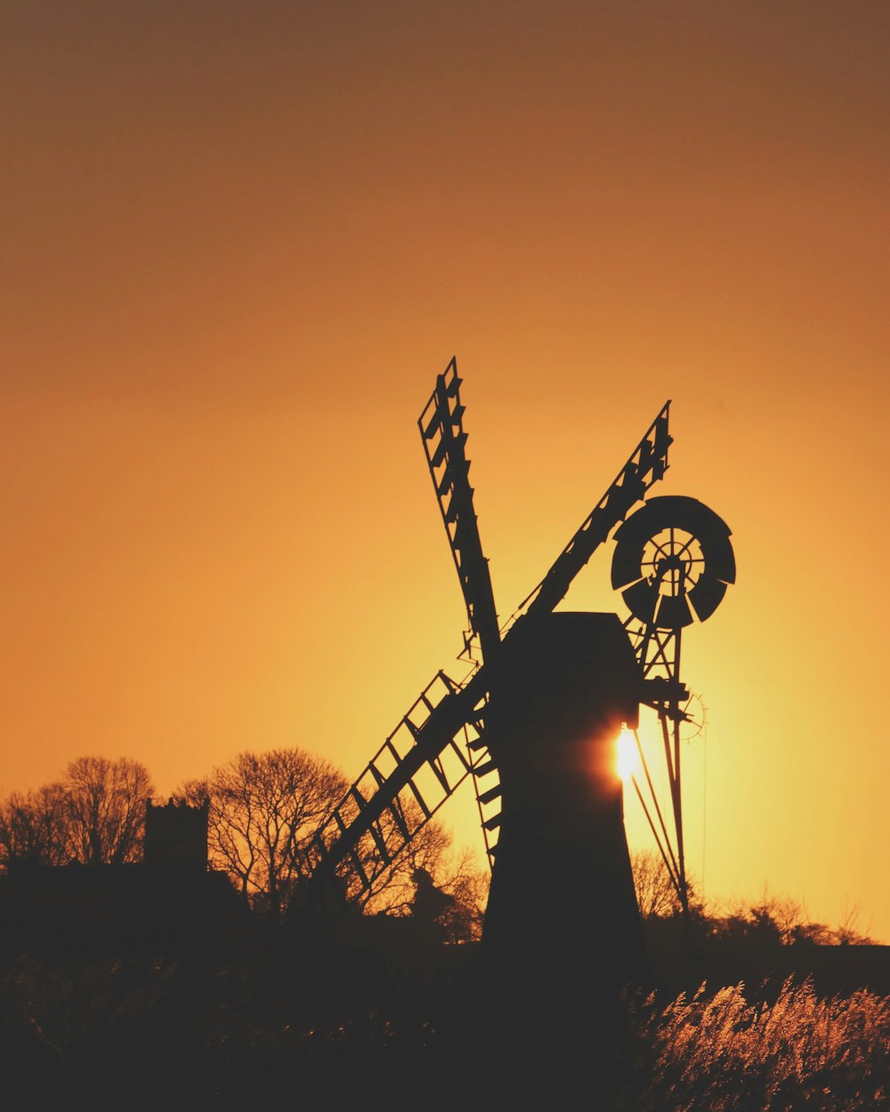 a windmill with the sun setting behind it