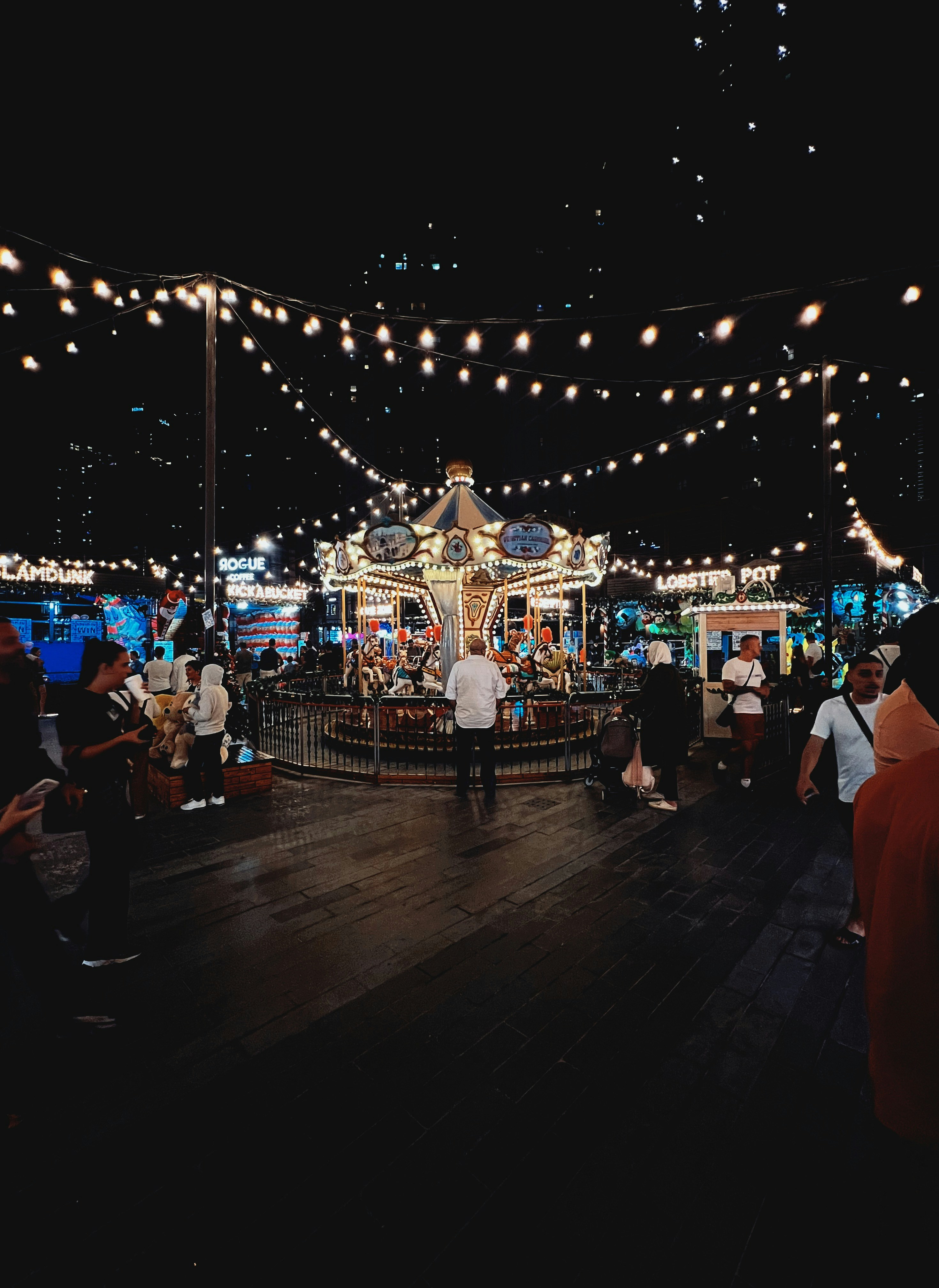 a group of people standing around a carousel at night