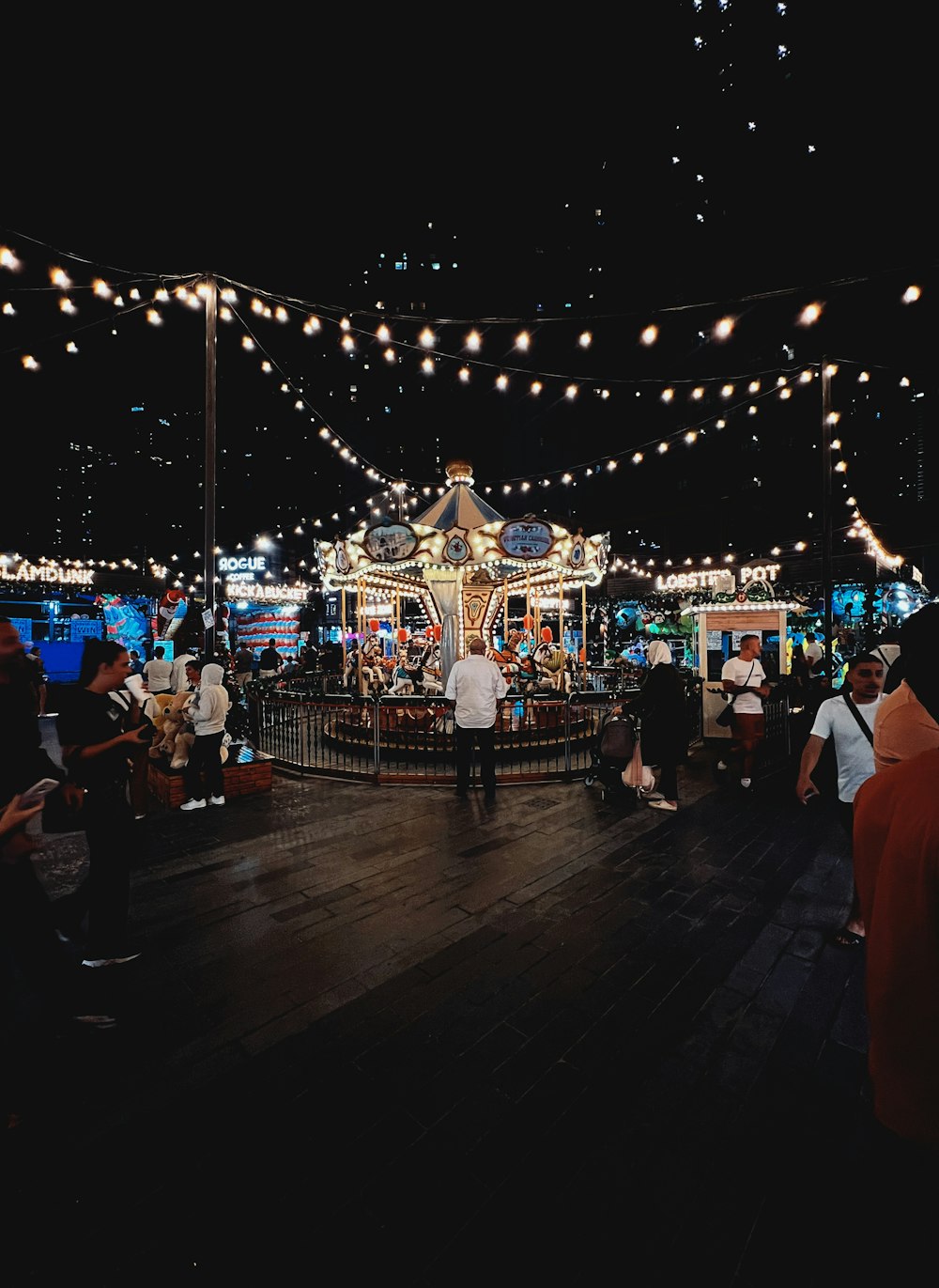 a group of people standing around a carousel at night