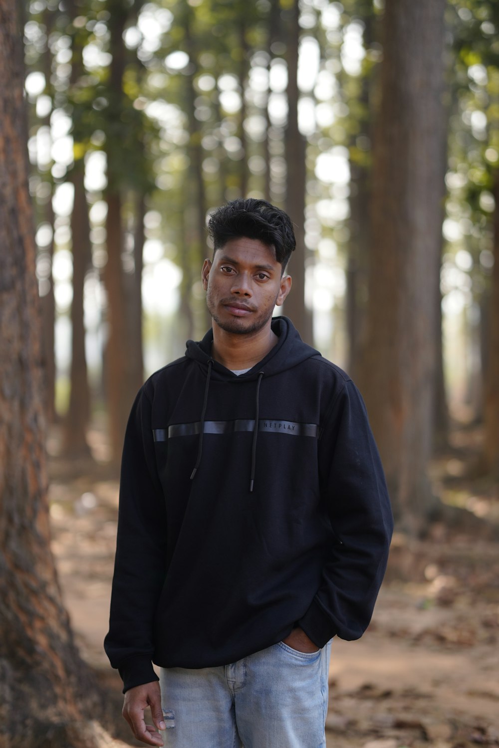 a man standing in front of a tree in a forest