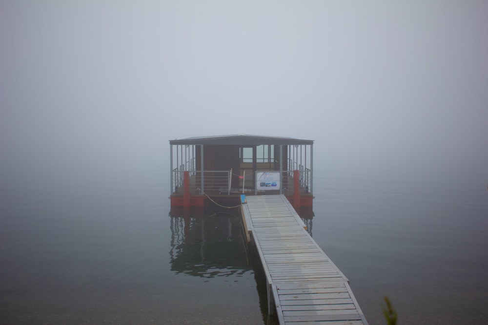 a dock with a small boat in the water on a foggy day
