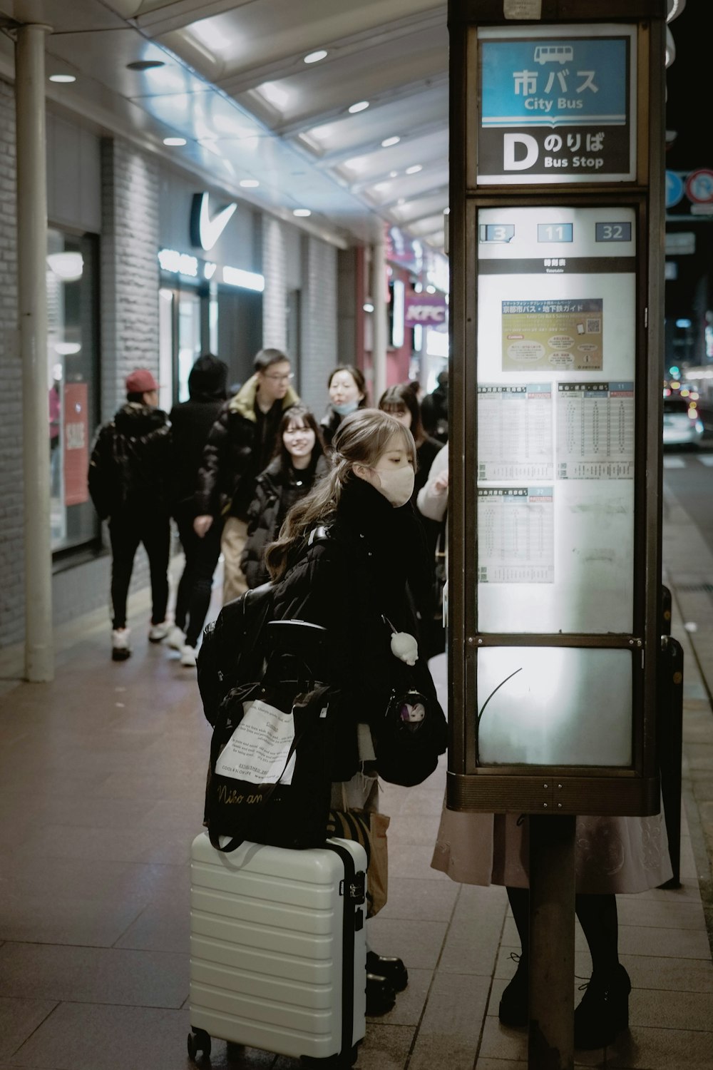 a group of people walking down a sidewalk next to a bus stop