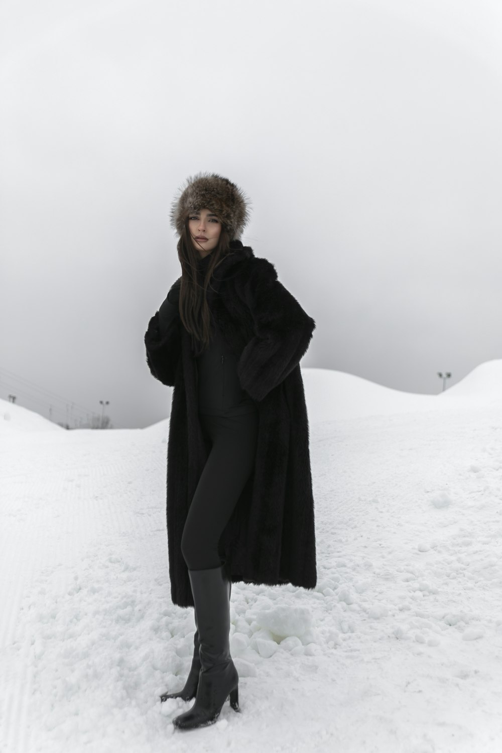 a woman standing in the snow wearing a fur coat