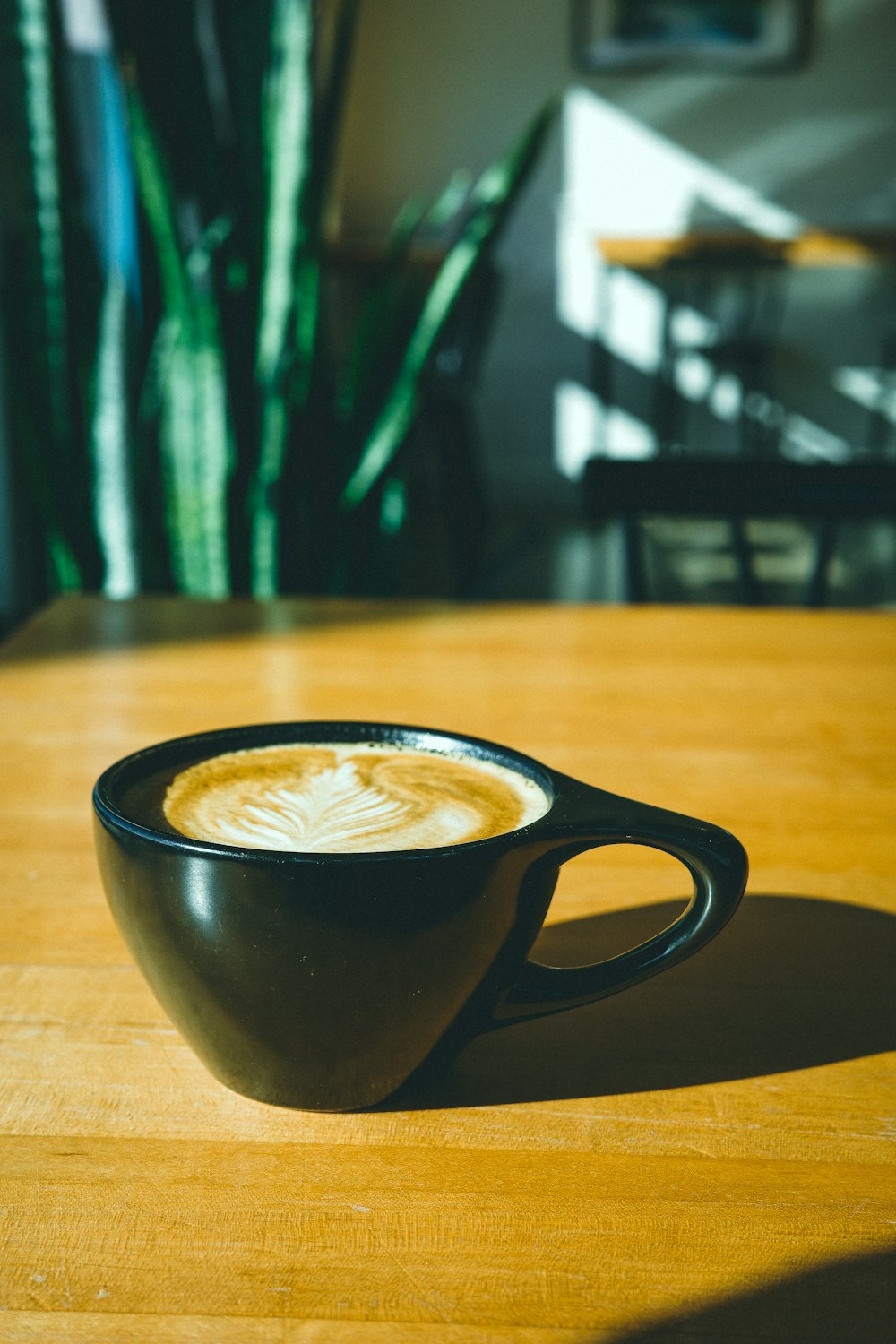 a cup of coffee sitting on top of a wooden table