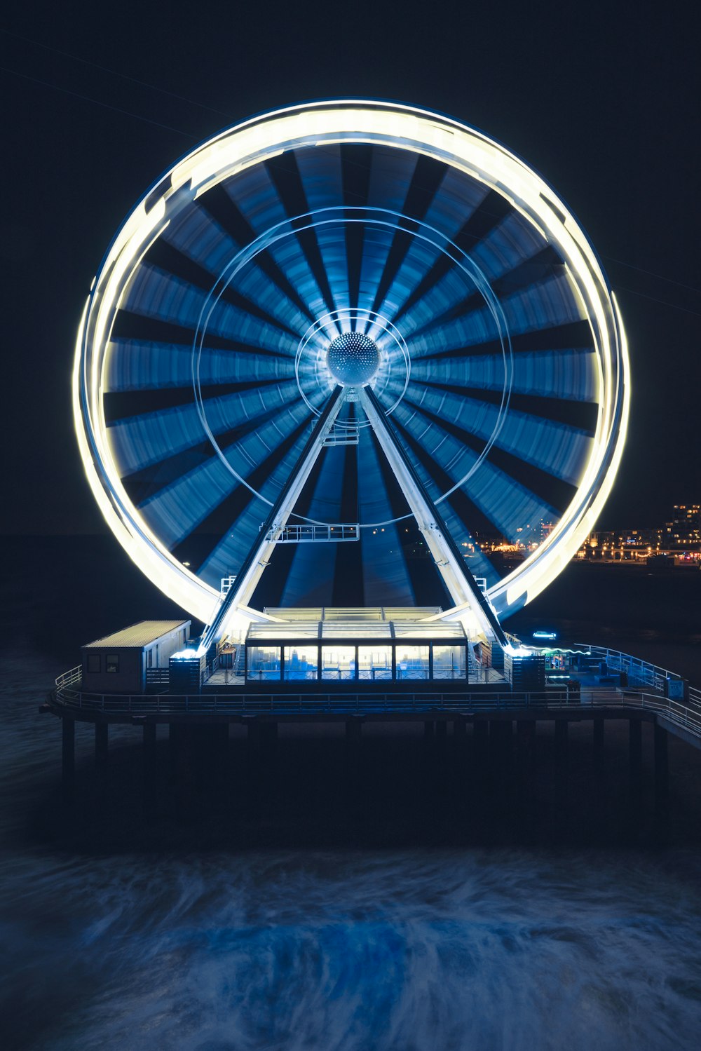a ferris wheel lit up at night on a pier