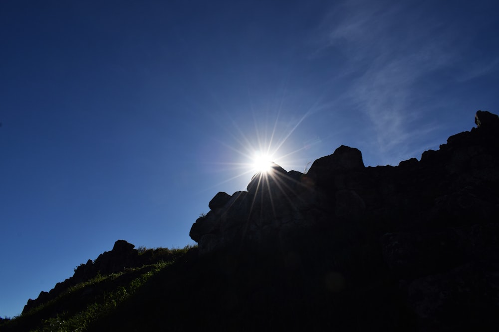 the sun is shining brightly over a rocky hill