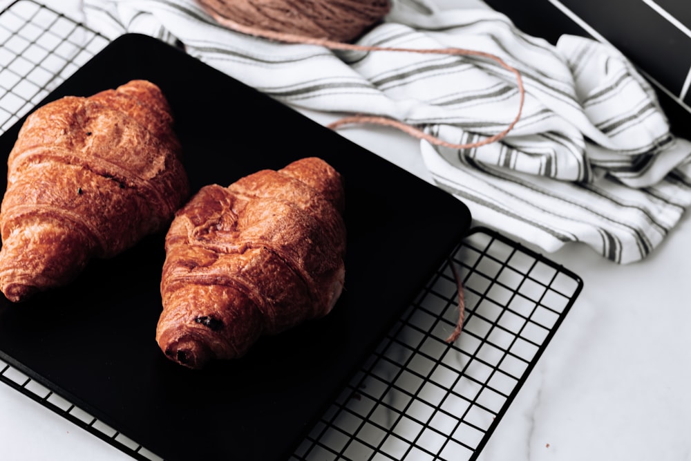 two croissants on a black plate on a cooling rack