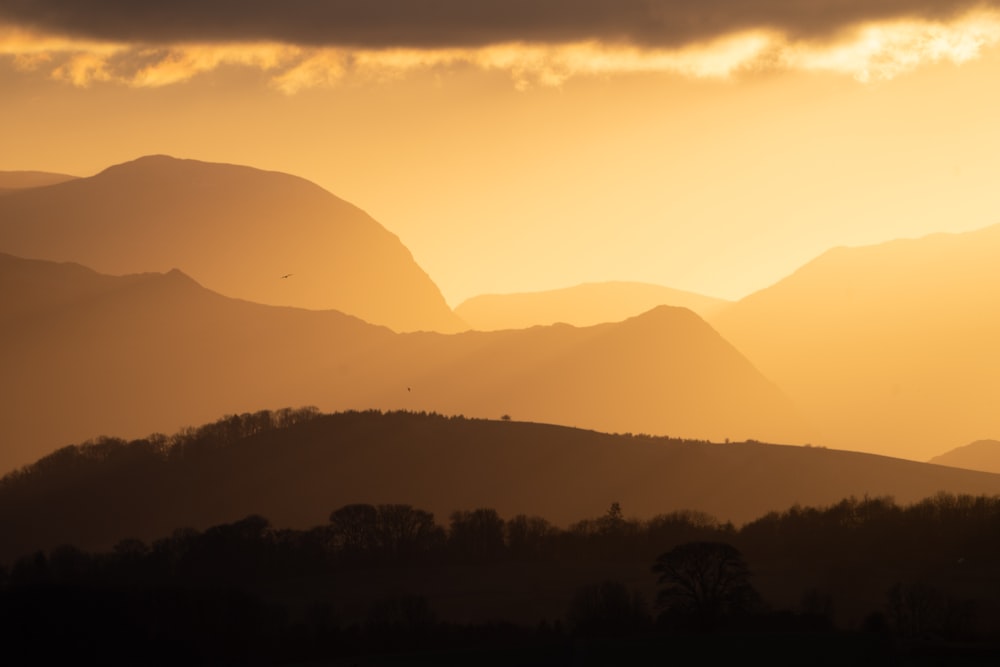 the sun is setting over a mountain range