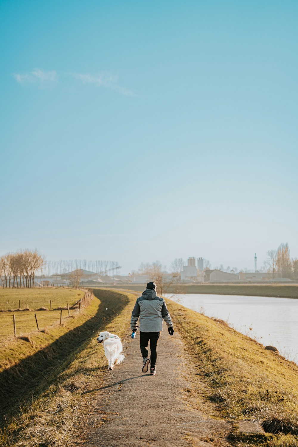 a person walking a dog down a dirt road