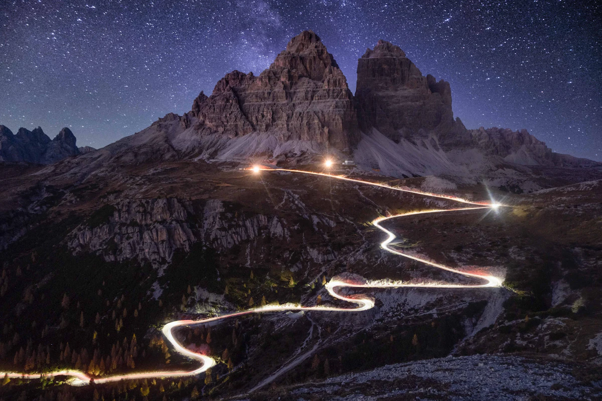 A mountain road winding through the Dolomites under a night sky