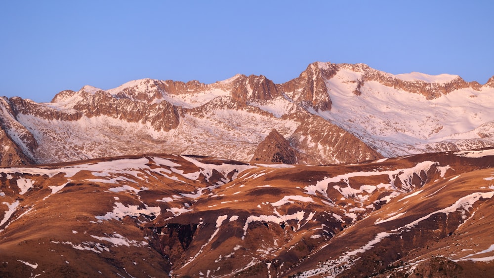 a mountain range covered in snow under a blue sky