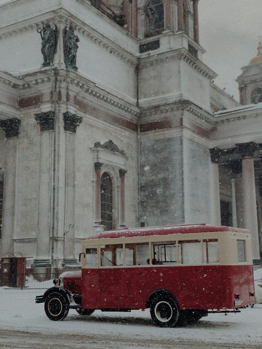 a red and white bus parked in front of a building