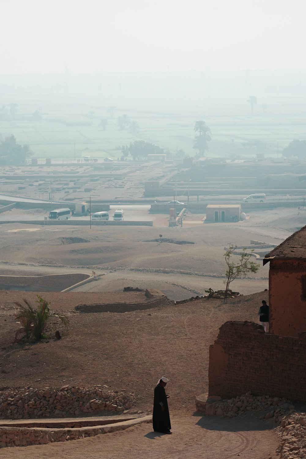 a person standing on a dirt road near a building