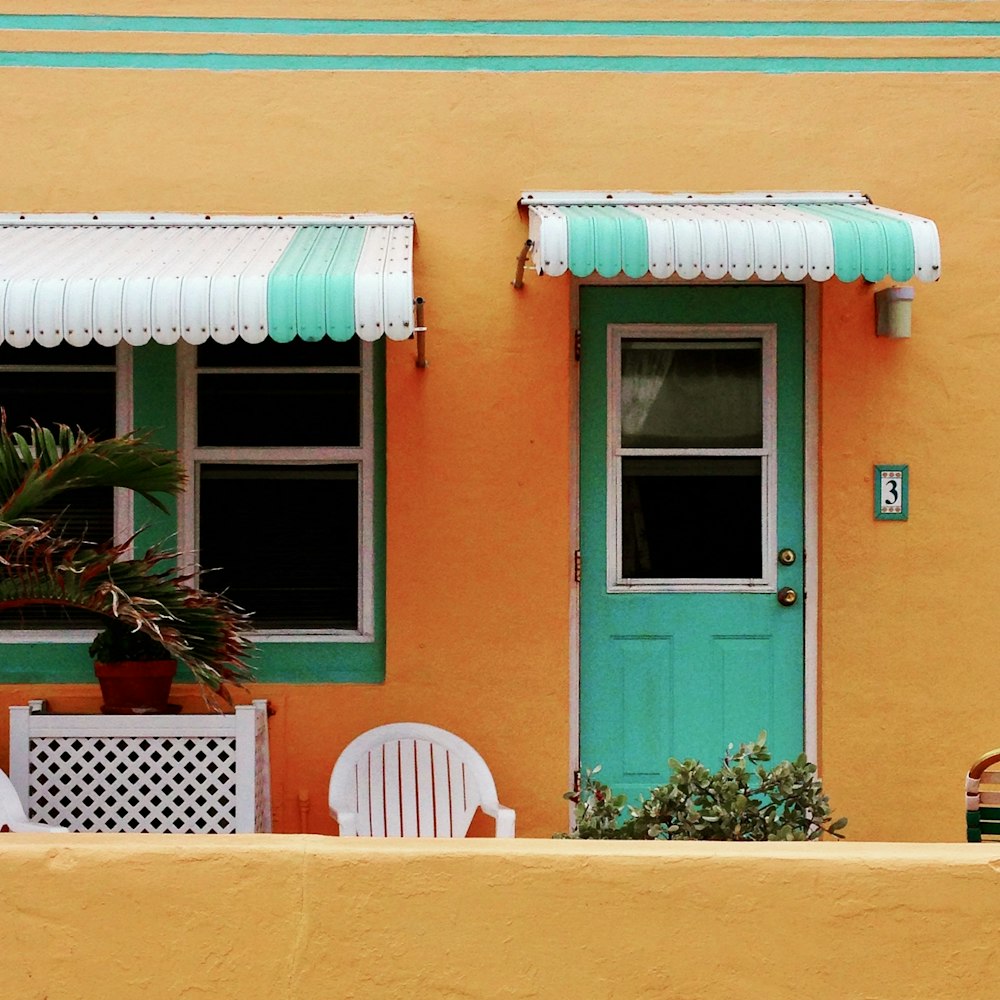 a yellow building with a green door and a green and white awning