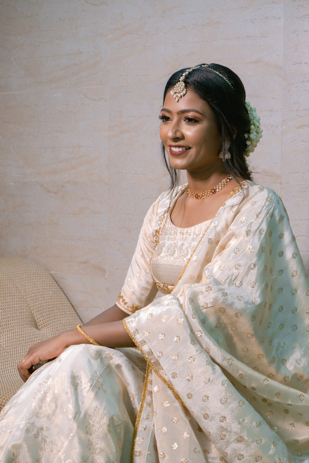 a woman in a white sari sitting on a couch