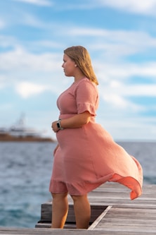 a woman in a pink dress standing on a dock