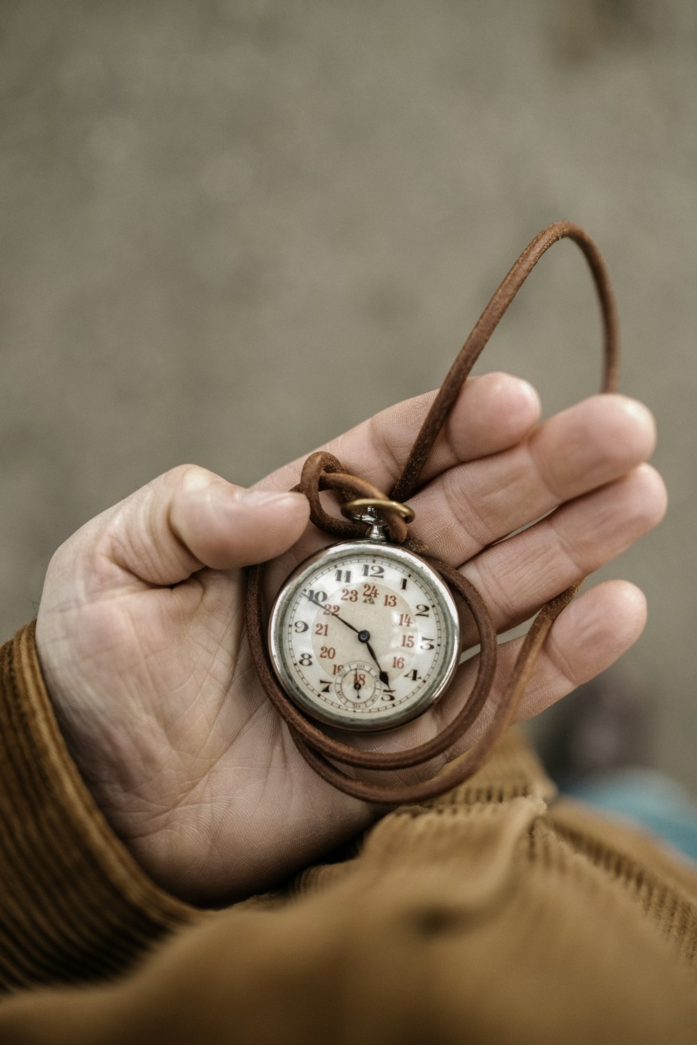 uma pessoa segurando um pequeno relógio de bolso na mão