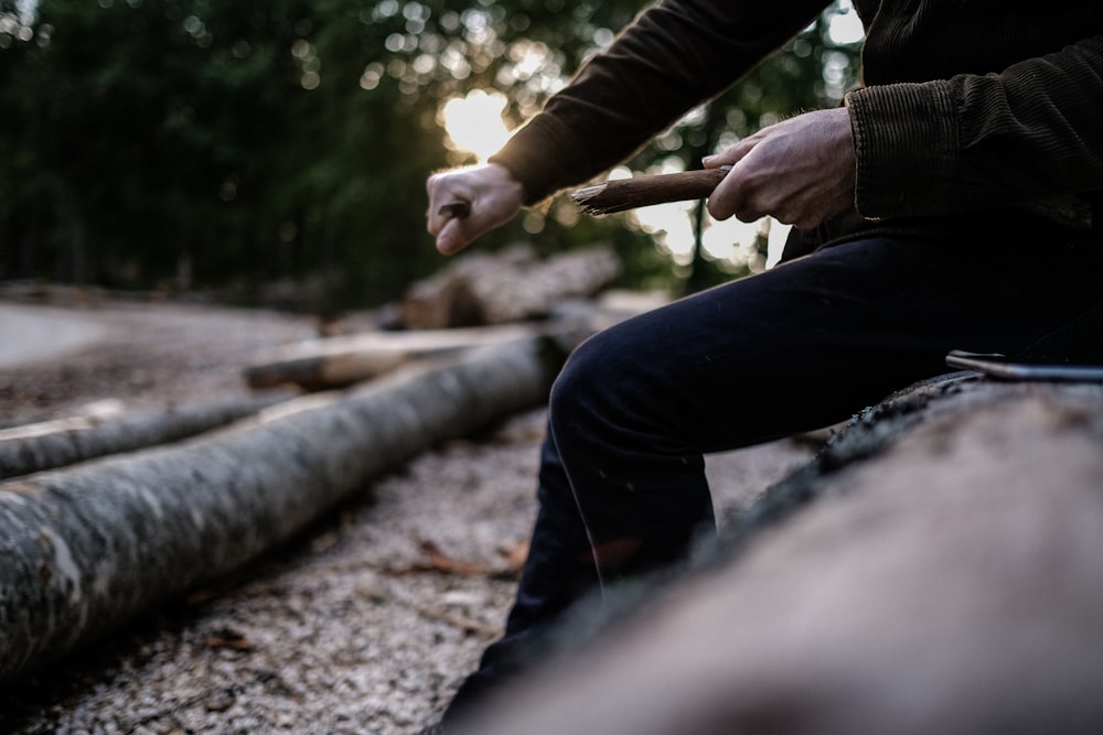 a person sitting on a log holding a stick