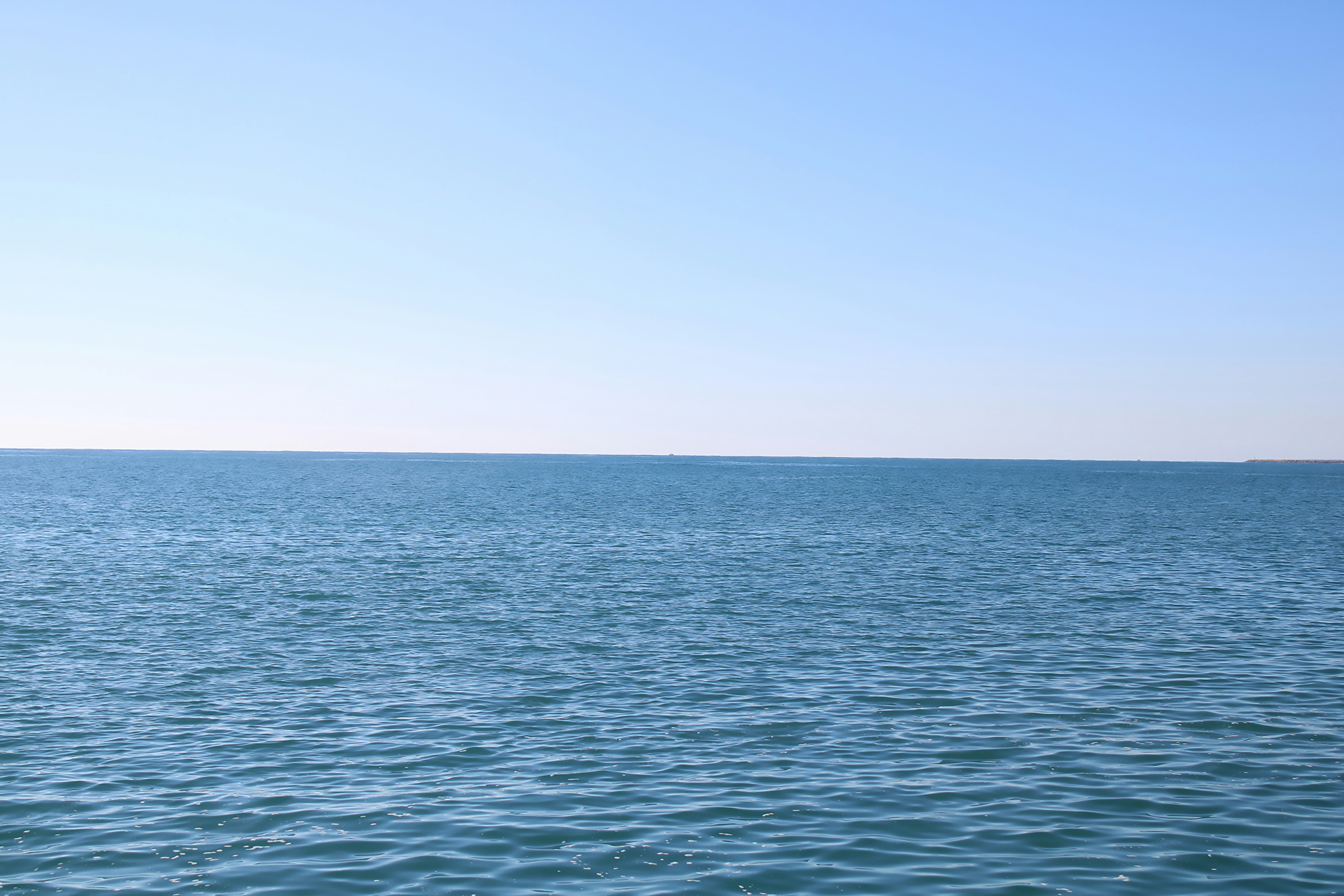Deep blue Pacific ocean surface viewed from a research vessel deck, calm waters, clear horizon, vast seascape