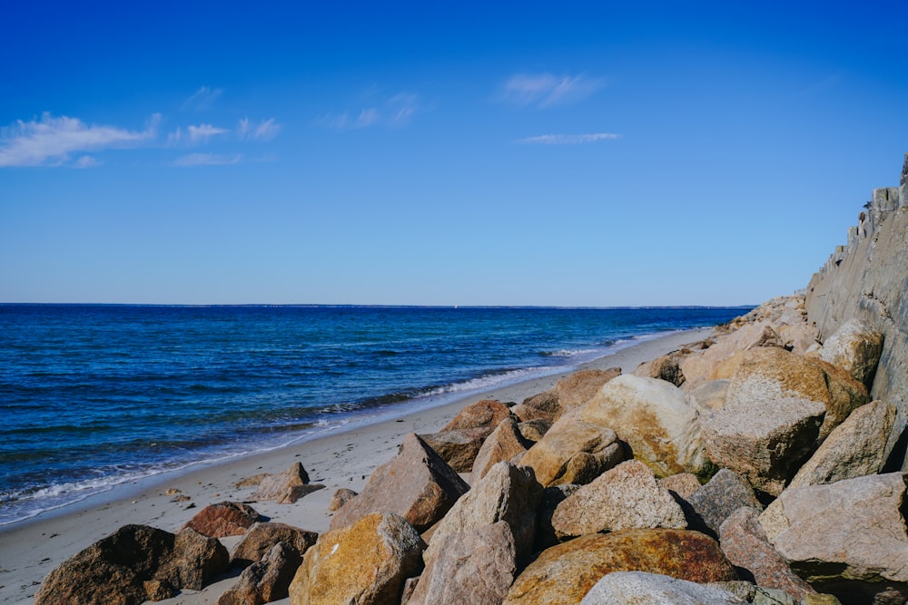 uma praia com pedras e água em um dia ensolarado