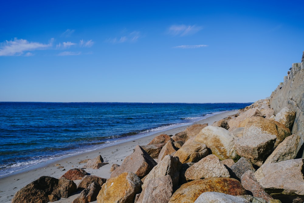 a beach with rocks and water on a sunny day