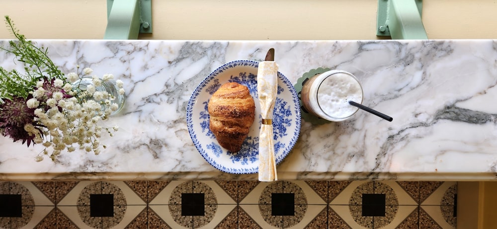 a plate with a croissant on it next to a bowl of yogur
