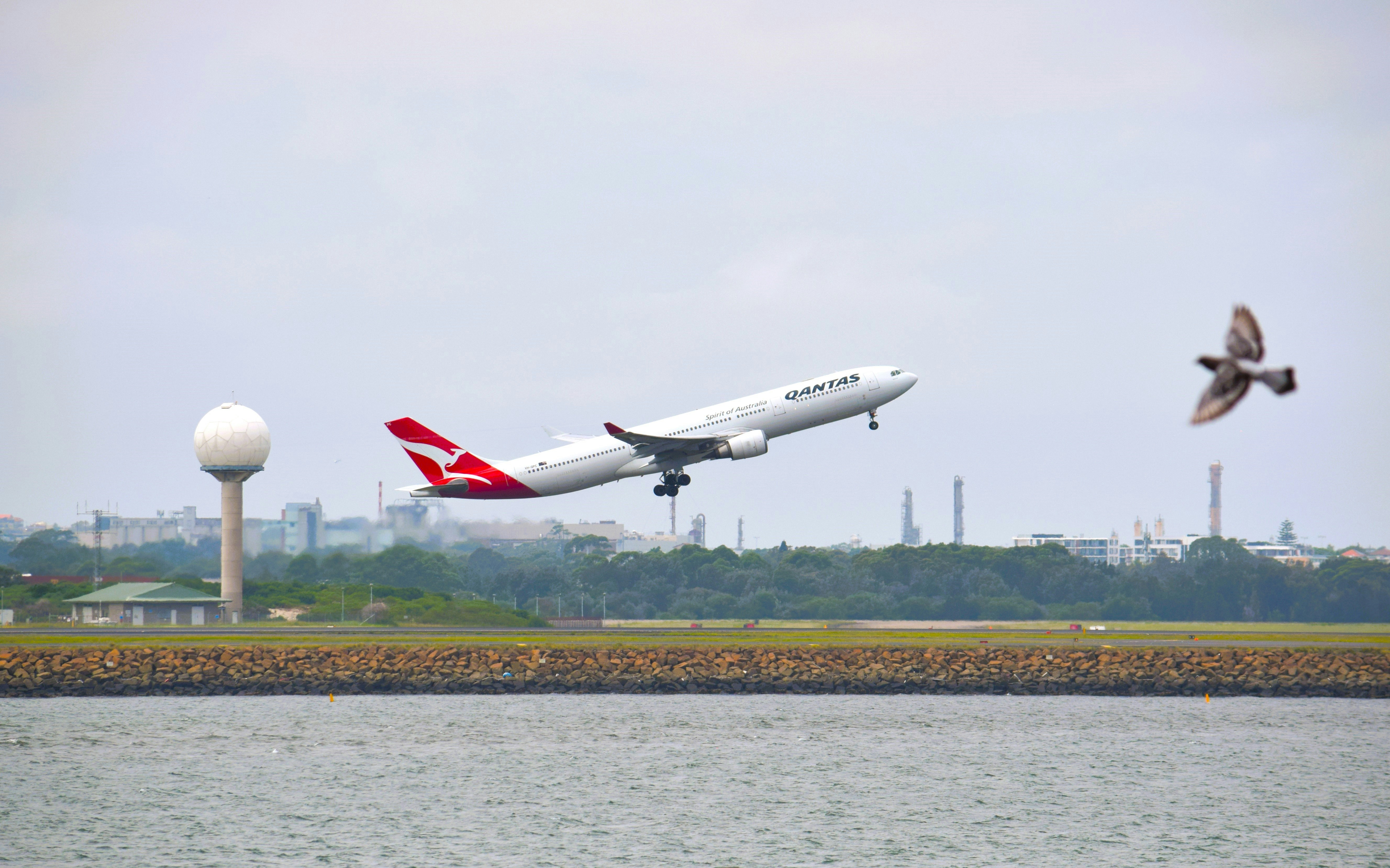 a large jetliner flying over a body of water, 