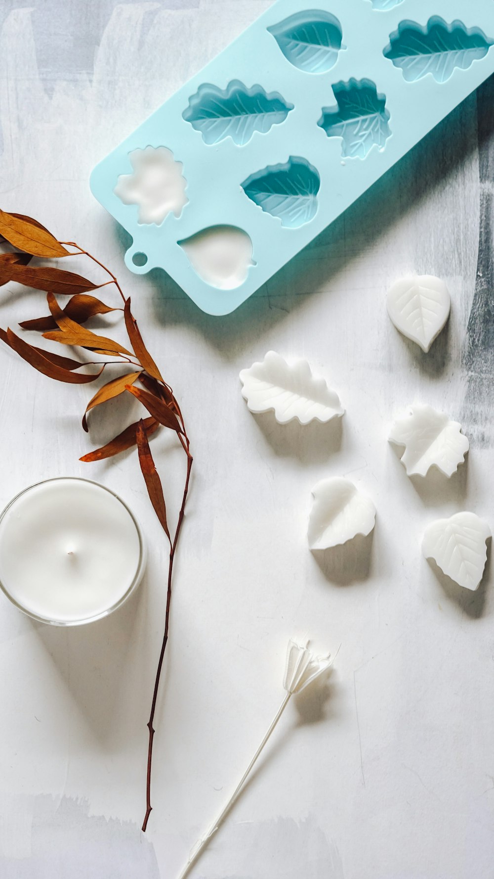 a cookie cutter, a candle and some leaves on a table