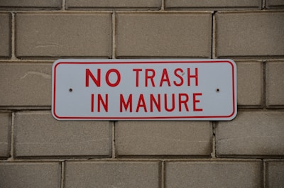 a no trash in manure sign on a brick wall