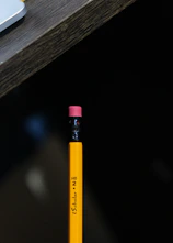 a yellow pencil sitting on top of a wooden table