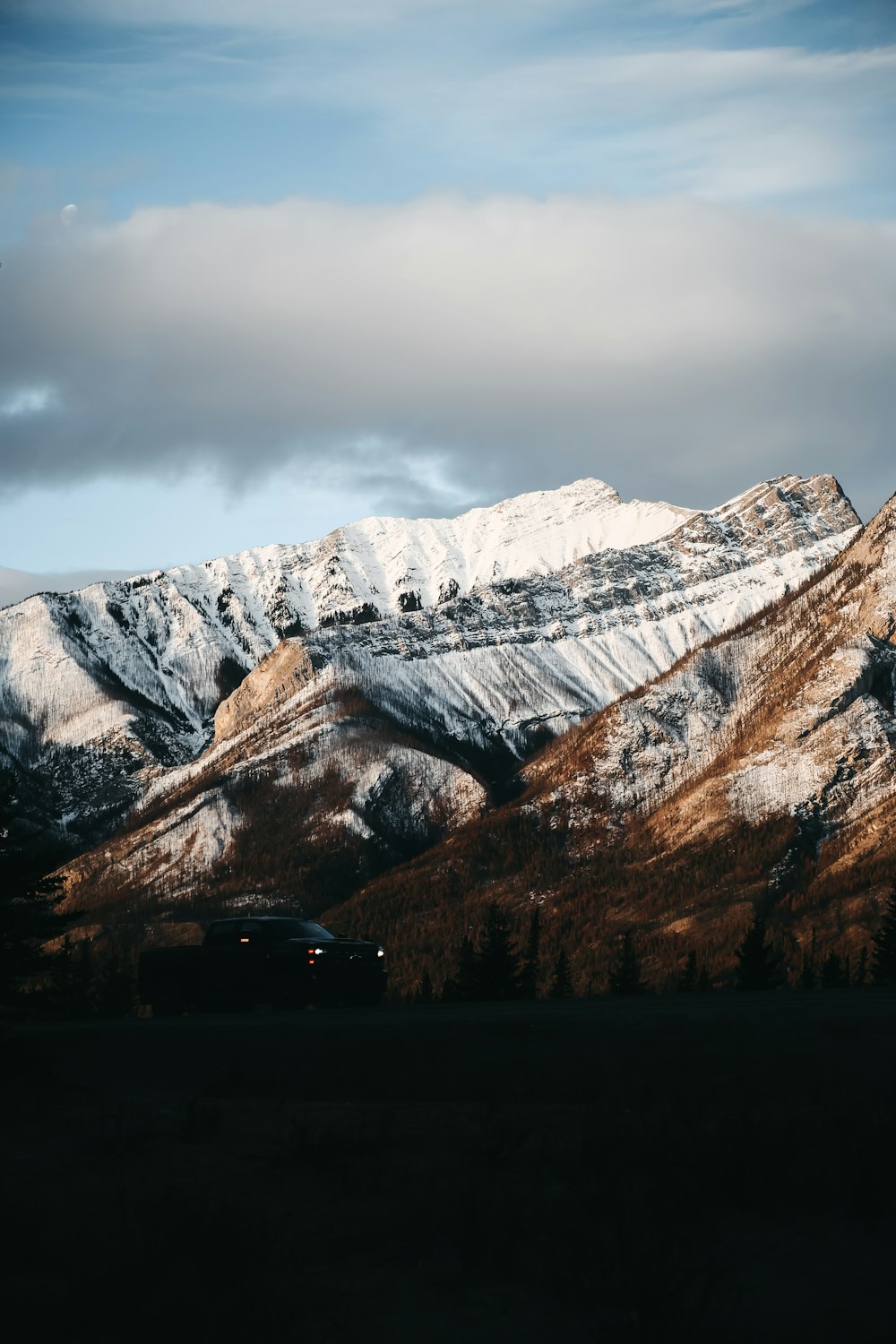 Un coche aparcado frente a una montaña cubierta de nieve
