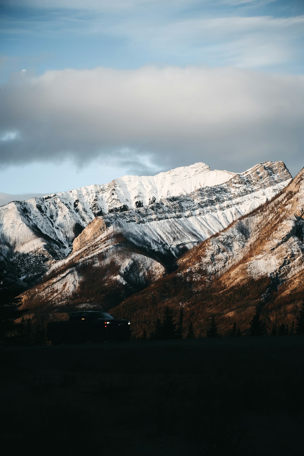 a car parked in front of a snow covered mountain