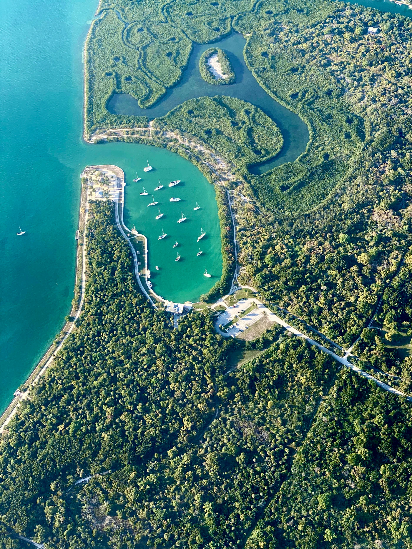 An aerial view of a wooded island point and a sheltered harbor, the kind of shoreline found at the southern tip of Key Biscayne.