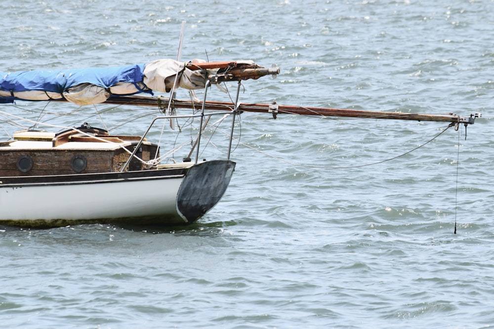 a sailboat with a blue tarp on it floating in the water