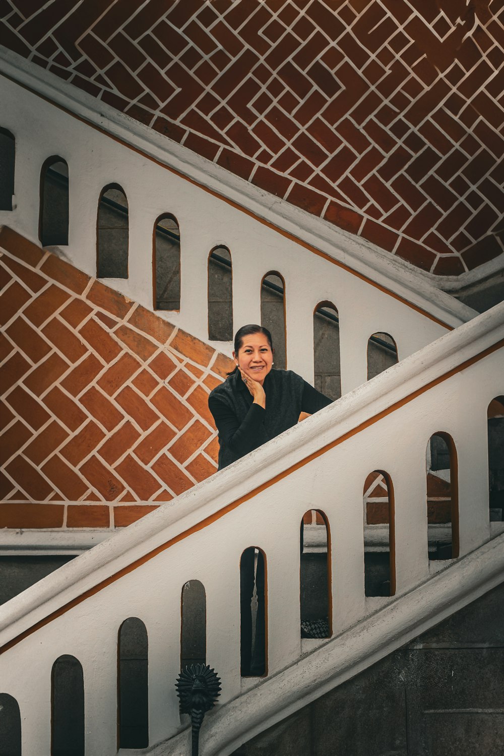 a woman standing on a stair case next to a brick wall