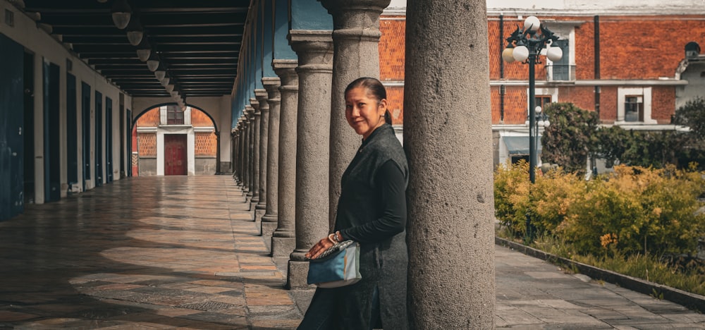 a woman leaning against a pillar in a building