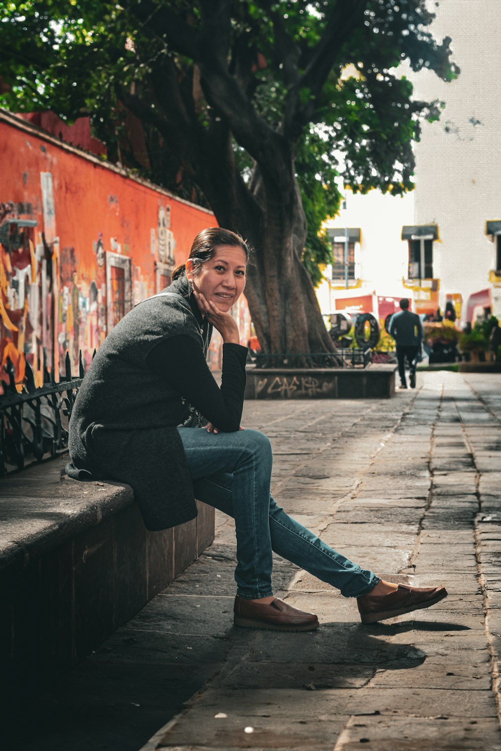 a woman sitting on a bench next to a tree