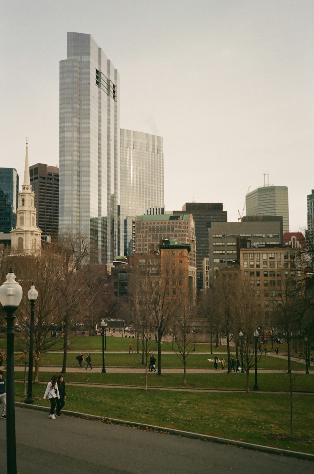 a couple of people walking down a street next to tall buildings