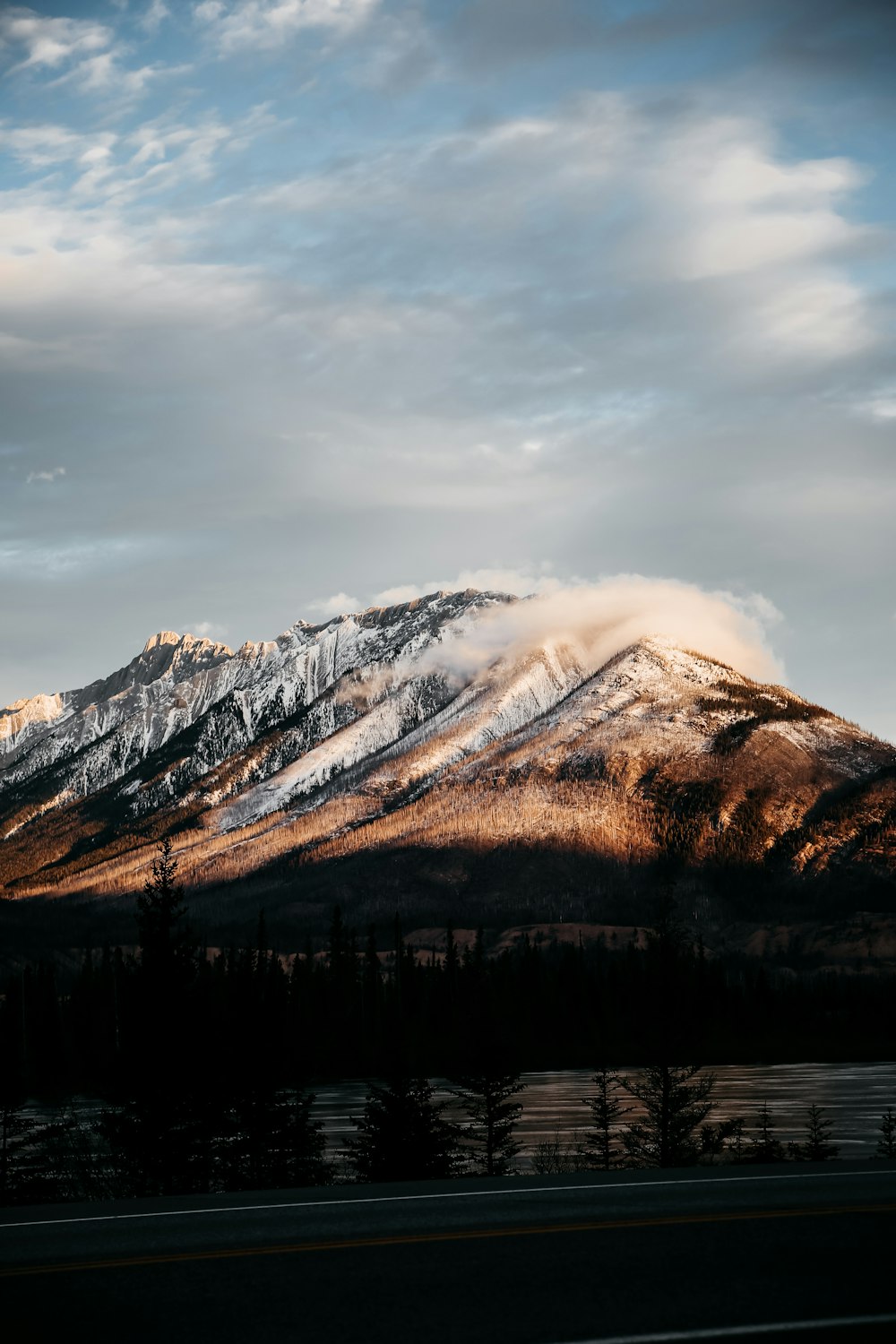 a mountain covered in snow under a cloudy sky