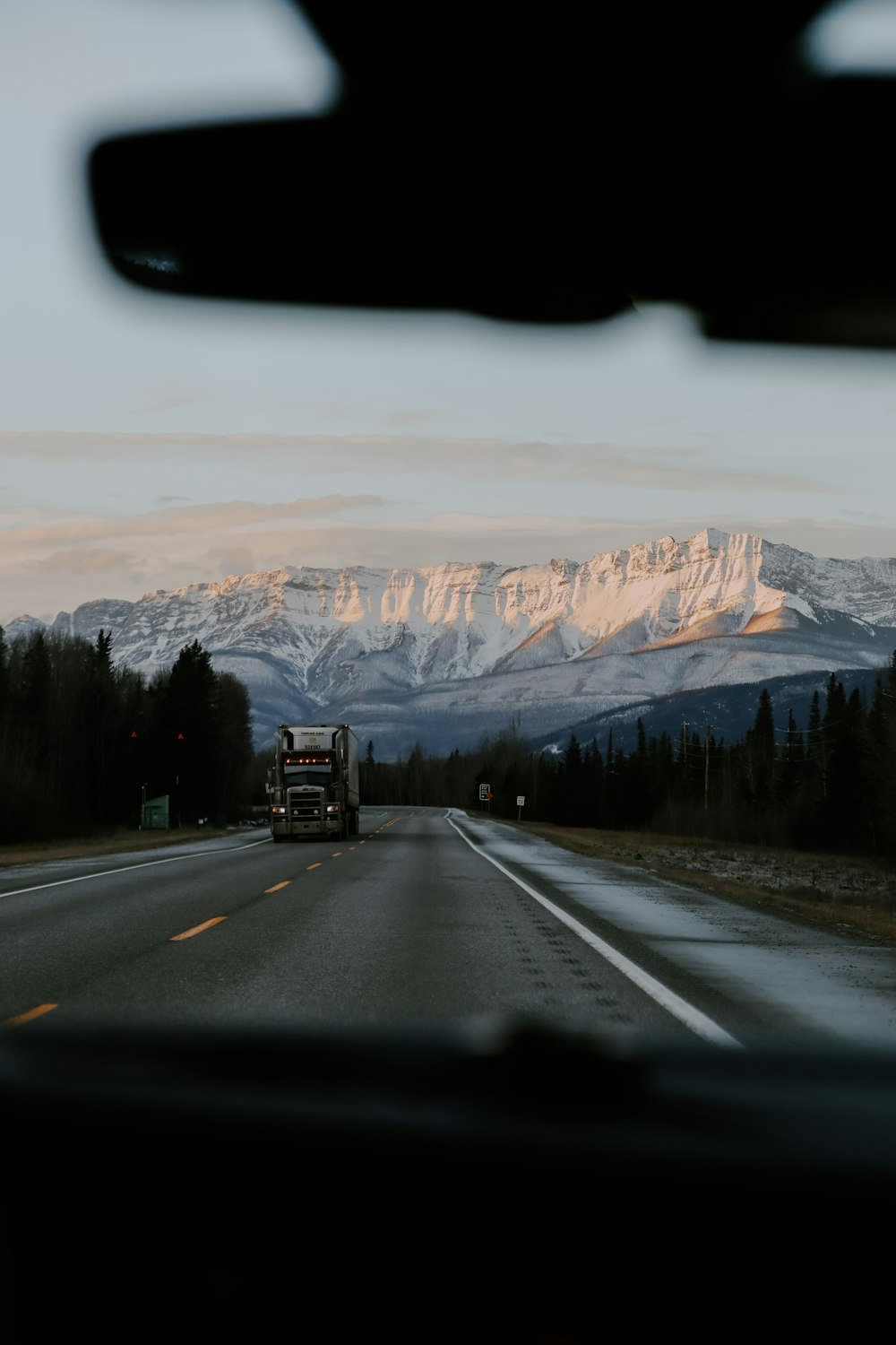 a truck driving down a highway with mountains in the background