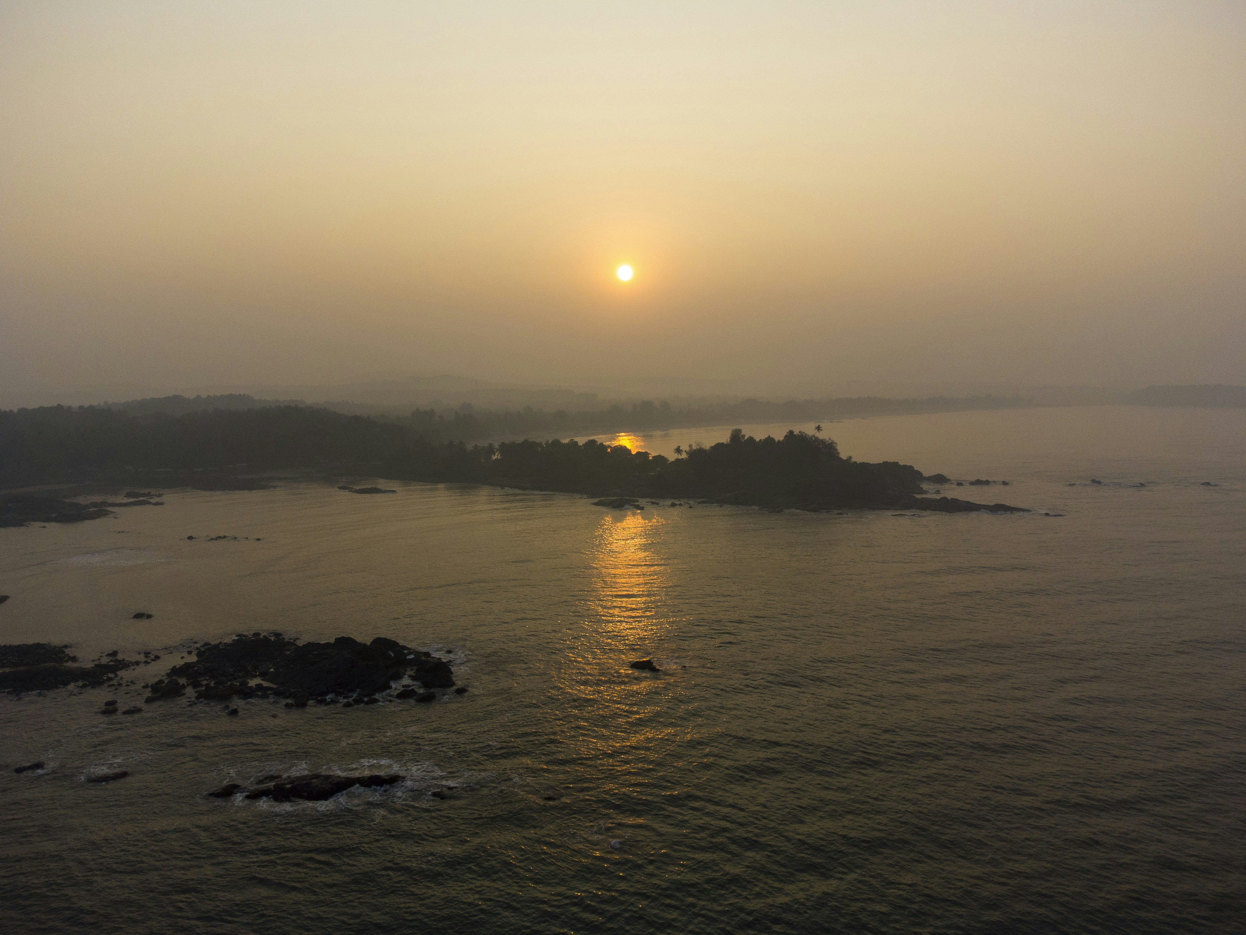 the sun is setting over a small island in the middle of the ocean