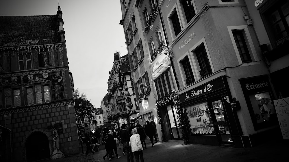 a group of people walking down a street next to tall buildings