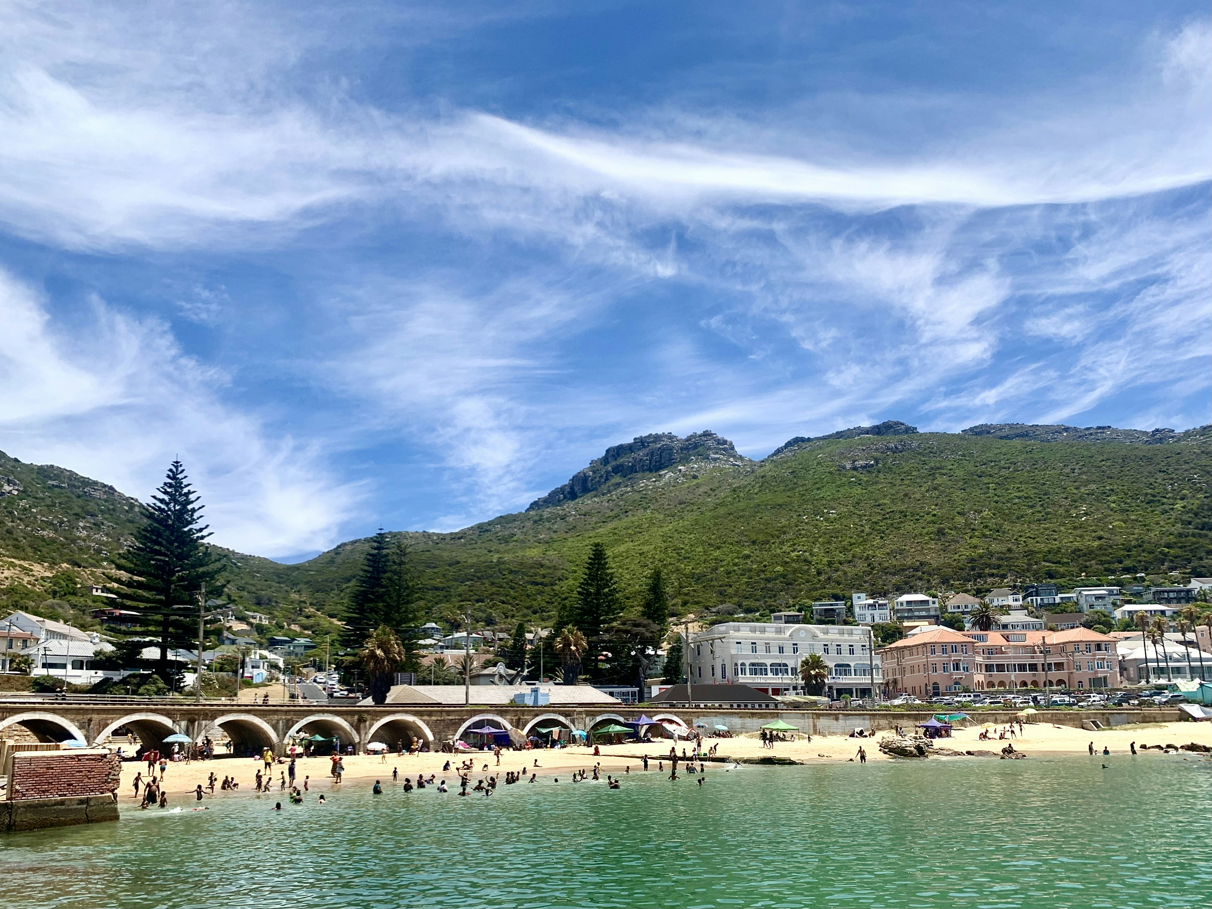 a group of people standing on a beach next to a body of water
