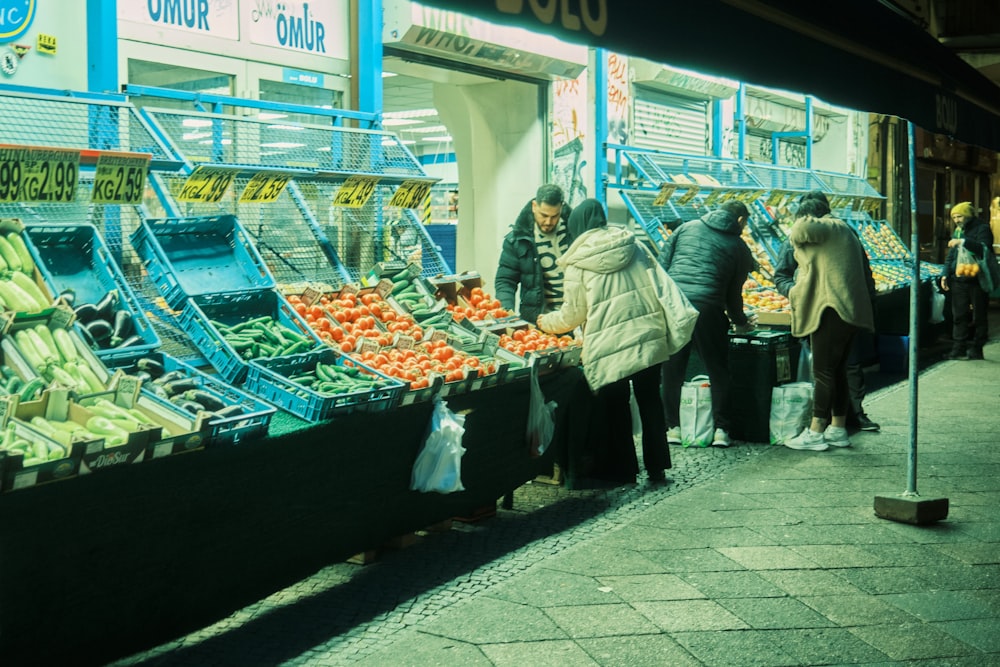 a group of people standing around a fruit stand