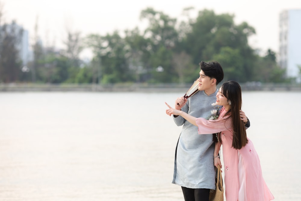 a man and a woman standing next to a body of water