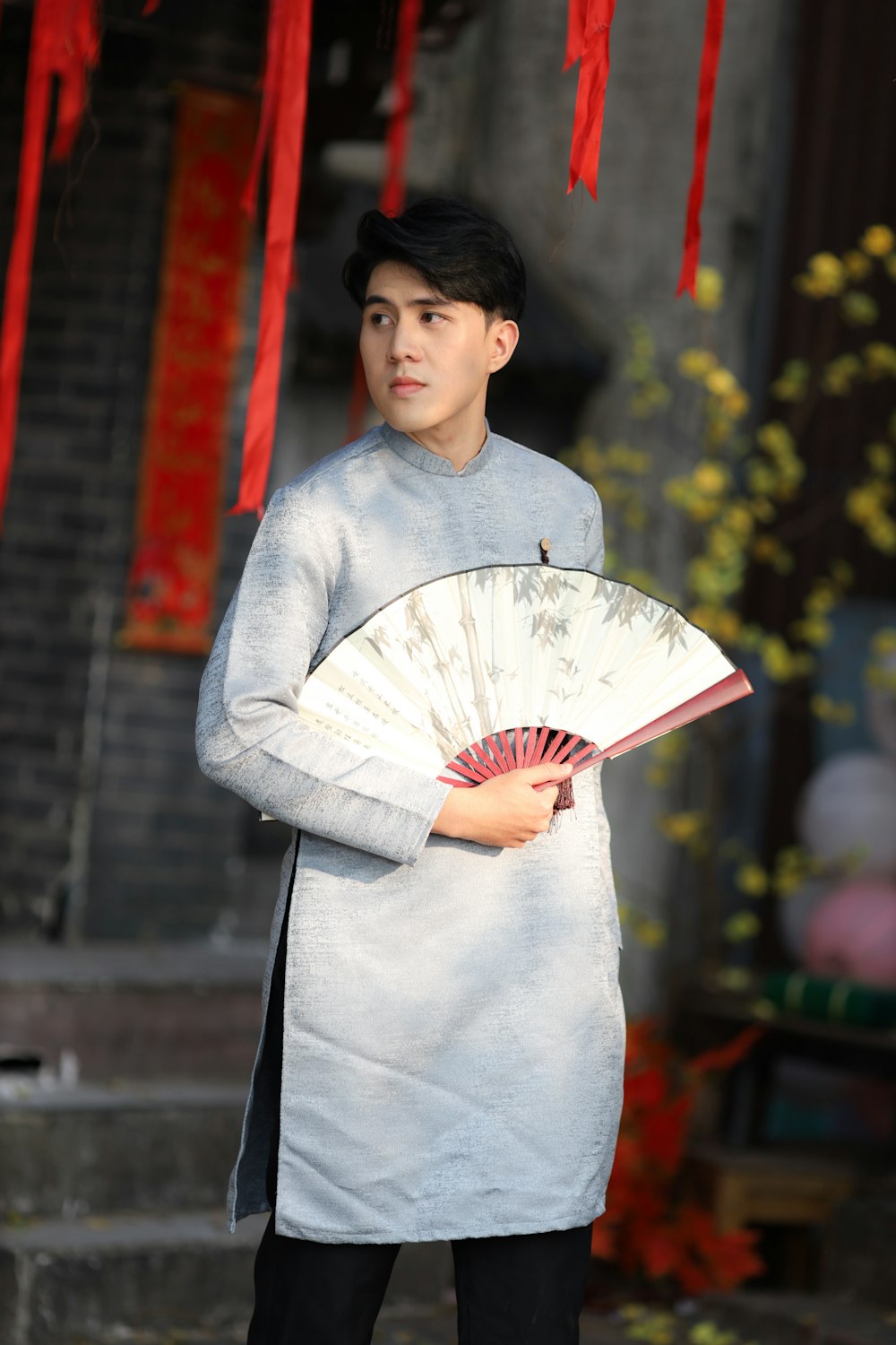 a man holding a fan standing in front of a building